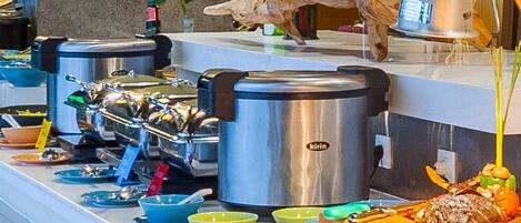 A buffet setup with various food items and kitchen appliances.