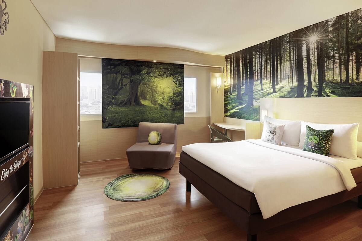 Una habitación de hotel con una cama grande, un escritorio, una silla y un televisor.