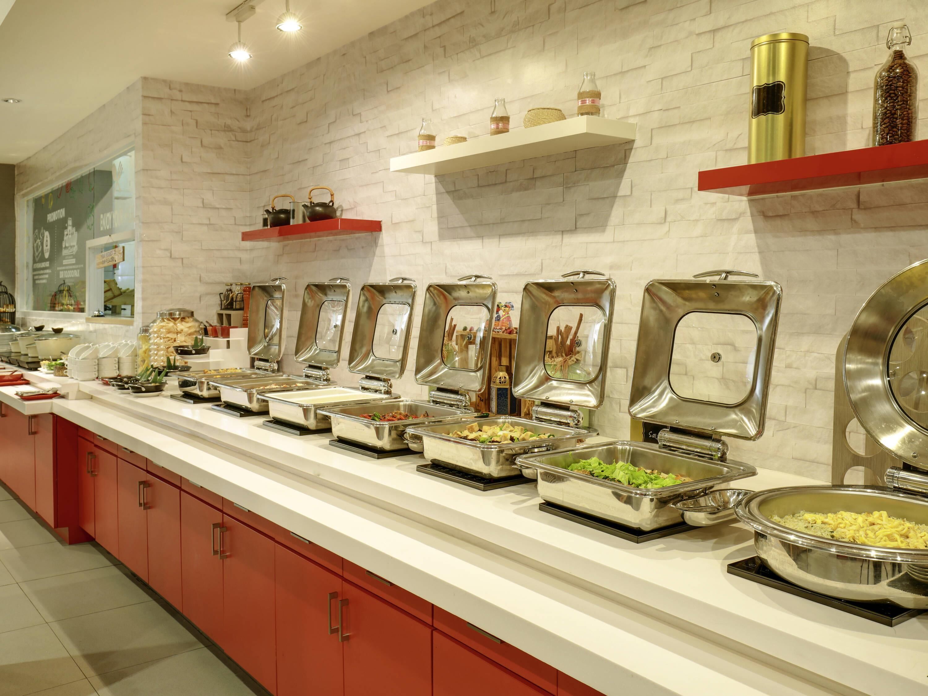 Un buffet avec différents postes de service et des ustensiles à disposition.