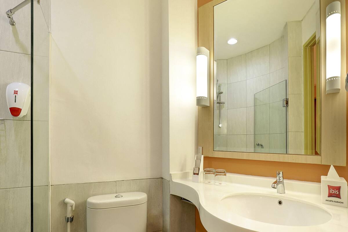 Un baño moderno con inodoro, lavamanos y cabina de ducha de vidrio.