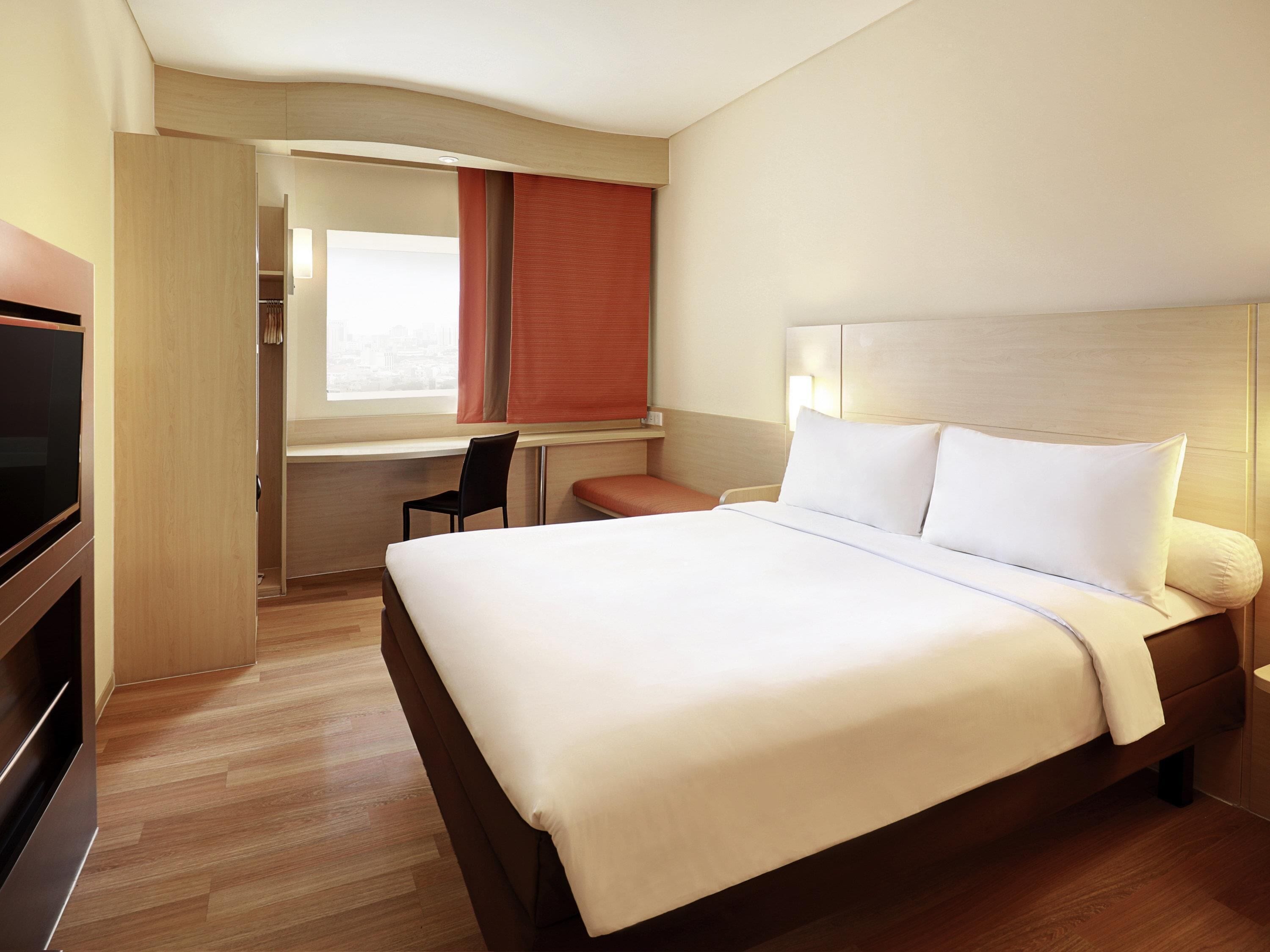 Une chambre d’hôtel avec un lit, un bureau et un téléviseur.