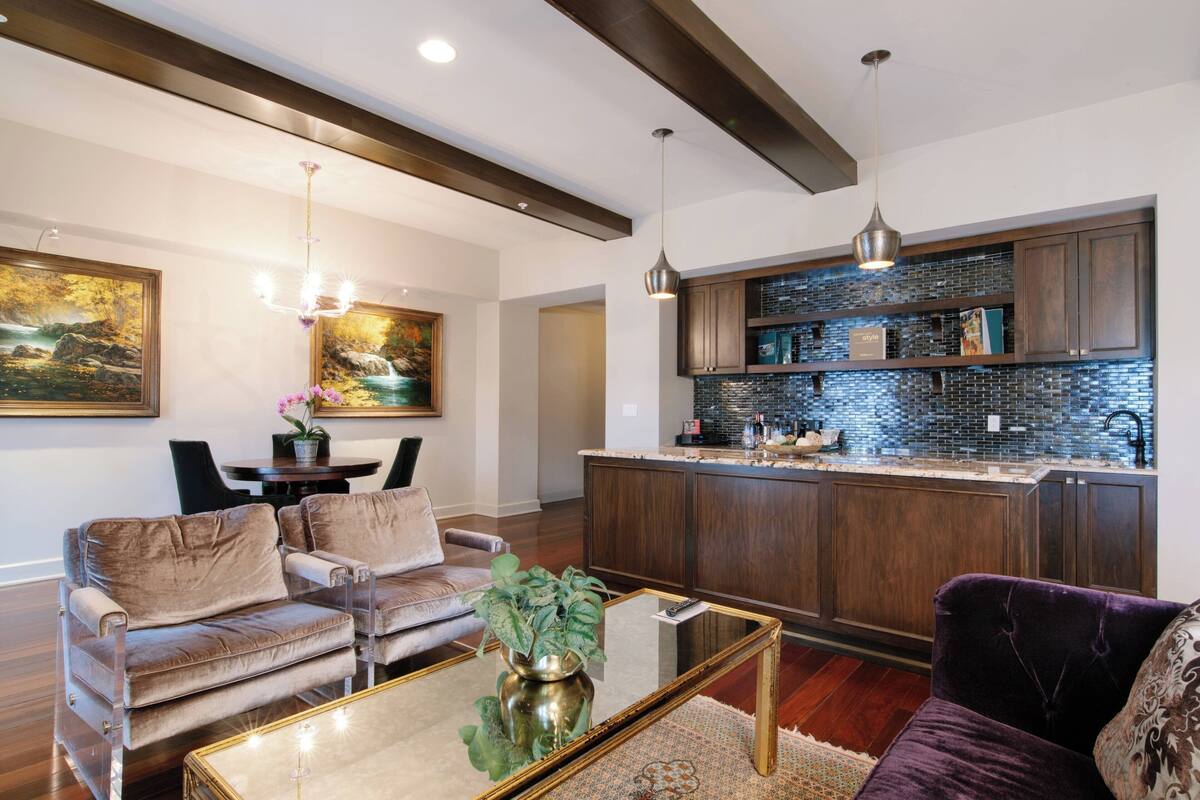 Un salon moderne comprenant un canapé, une table basse et un coin cuisine avec un mur recouvert de carreaux.