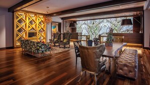 A spacious room with a wooden floor, a dining area with a bench, and a seating area with patterned sofas. - Grand Bohemian Mountain Brook, Autograph Collection (Birmingham)