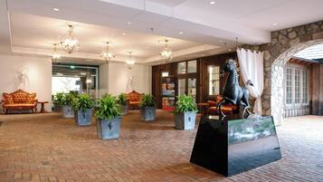 Eine Lobby mit Terrazzoboden, Blumentöpfen, einer Statue und einer Steinwand.