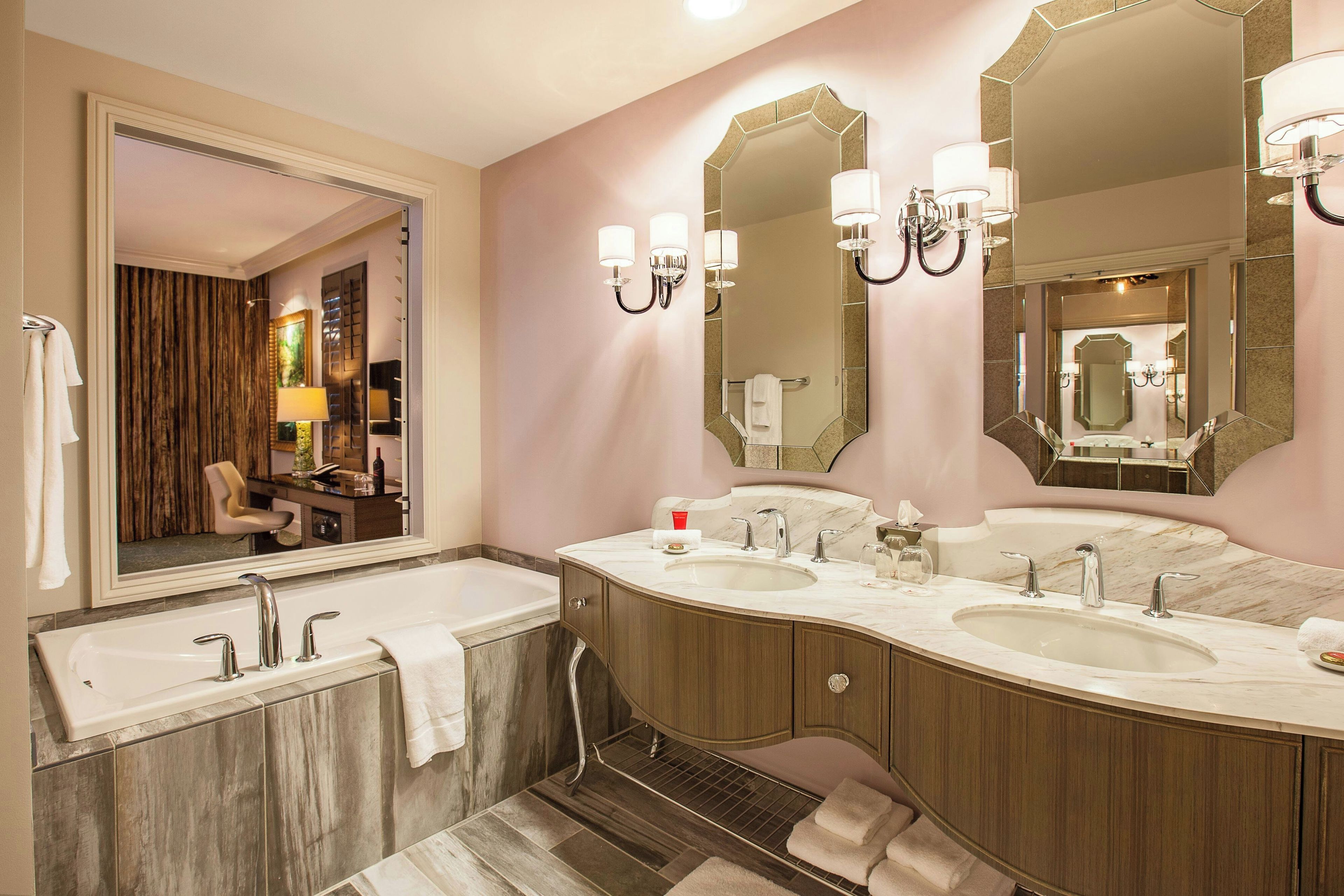 Un baño moderno con tocador doble, espejos grandes y bañera.