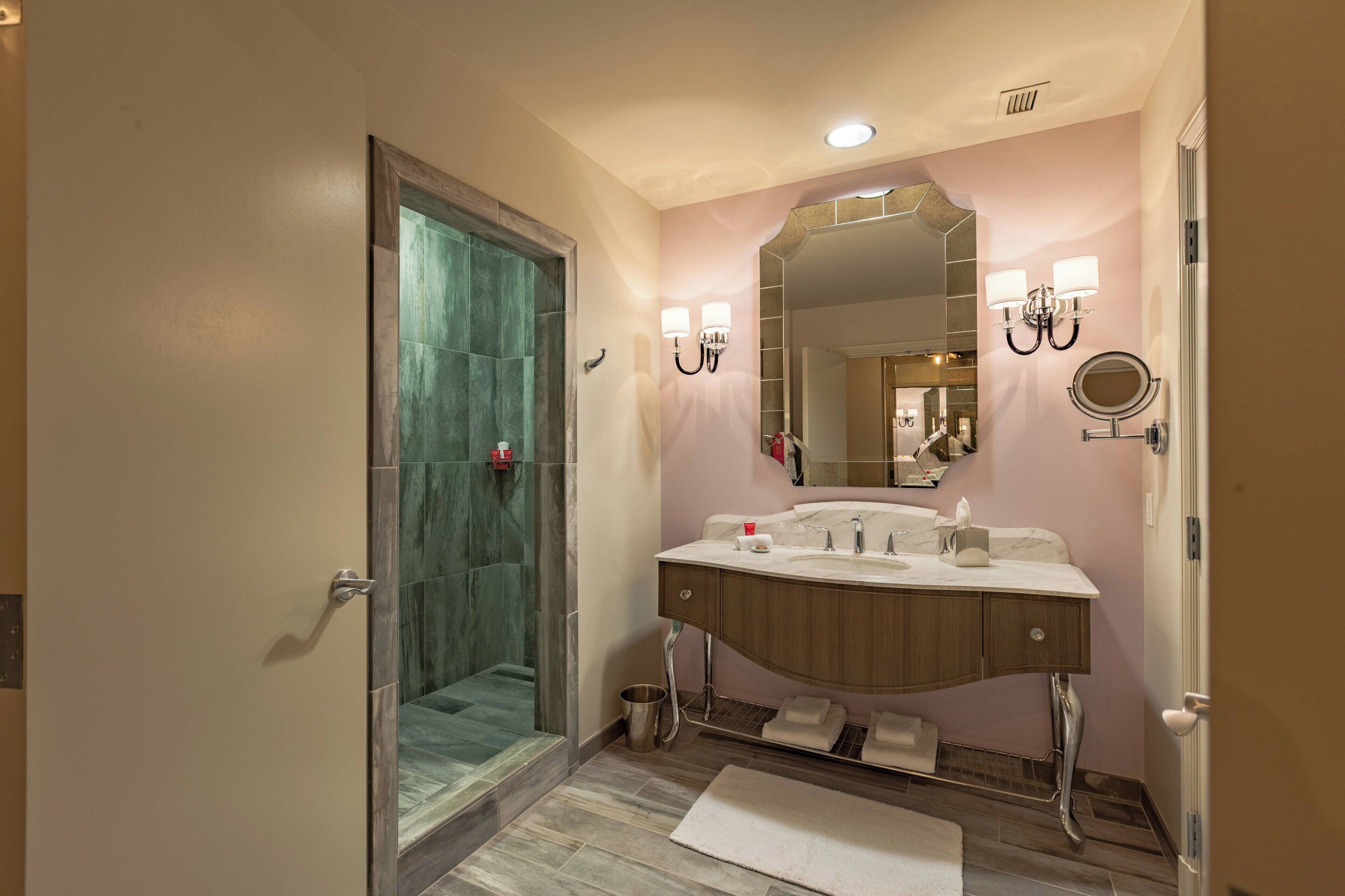 A bathroom with a shower, a sink with a mirror, and a towel rack.