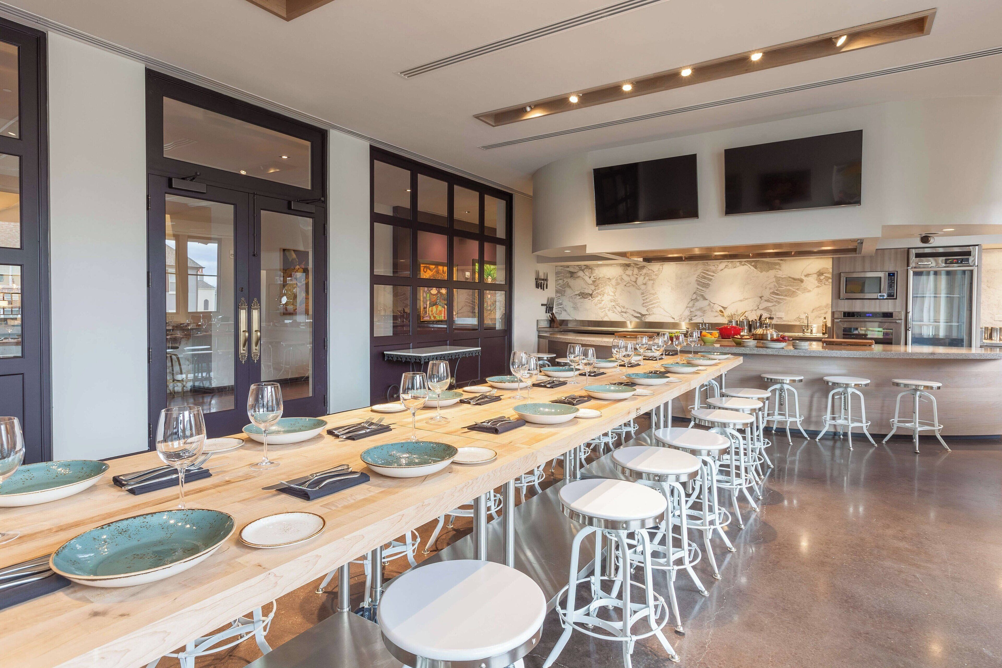 A modern kitchen with a long dining table, bar stools, and built-in appliances.