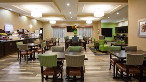 A hotel dining area with multiple tables and chairs, a buffet, and a television screen. - Holiday Inn Express & Suites Davenport by IHG (Davenport)