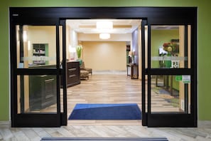 A hotel reception area with a reception desk, a waiting area with a sofa, and a hallway leading to other rooms. - Holiday Inn Express & Suites Davenport by IHG (Davenport)
