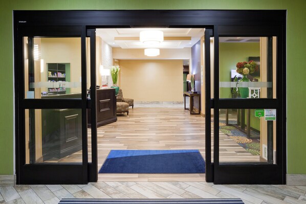 A hotel reception area with a reception desk, a waiting area with a sofa, and a hallway leading to other rooms.