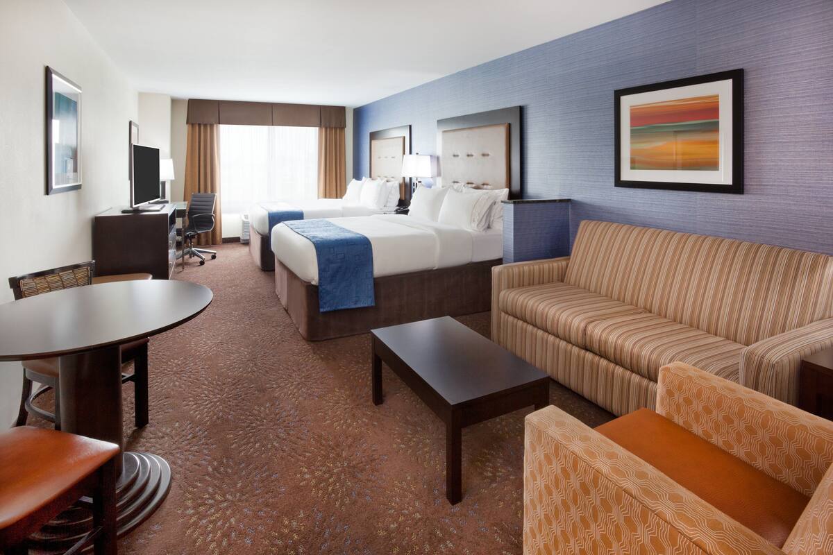A hotel room with a bed, a sofa, a desk, and a TV.