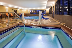 An indoor swimming pool with clear water, a lifeguard chair, and a pool ladder. - Holiday Inn Express & Suites Davenport by IHG (Davenport)