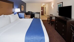 A hotel room with a large bed, a desk with a computer, a television, and a small seating area.