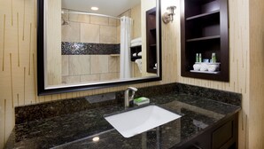 A bathroom with a large mirror, a sink, and a shower.
