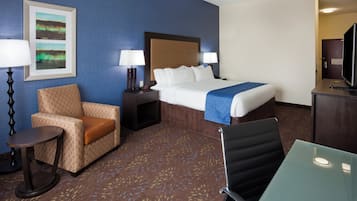 A hotel room with a bed, a chair, a desk, a lamp, and a television.