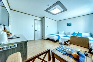 Ein Hotelzimmer mit Bett, Schreibtisch mit Computer, Stuhl und kleinem Tisch mit Teekanne und Tassen.