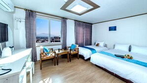 A hotel room with a desk, two beds, a skylight, and a view of the city.
