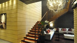 Un intérieur moderne avec un escalier, un lustre et un coin salon.