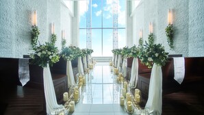 Une allée d’église décorée de draperies blanches, de bougies et de compositions florales.