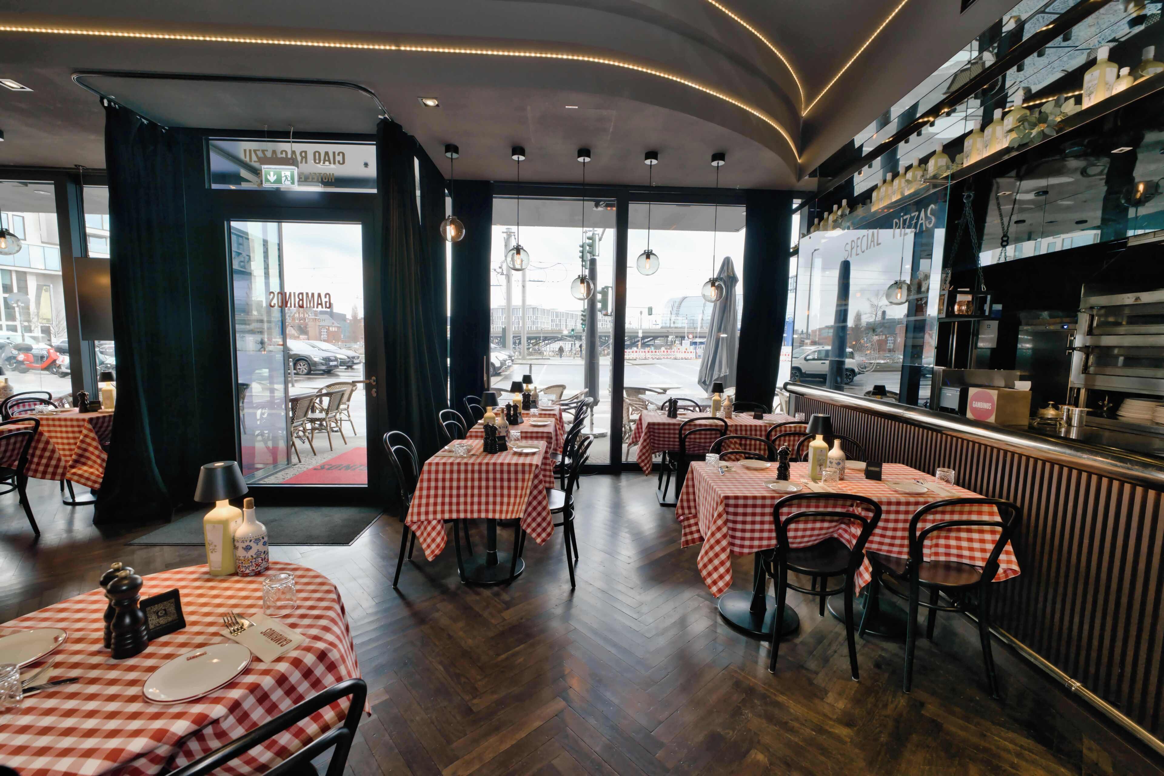 Ein Restaurantinneres mit karierten Tischdecken, Holzböden und Blick durch die Glastür.