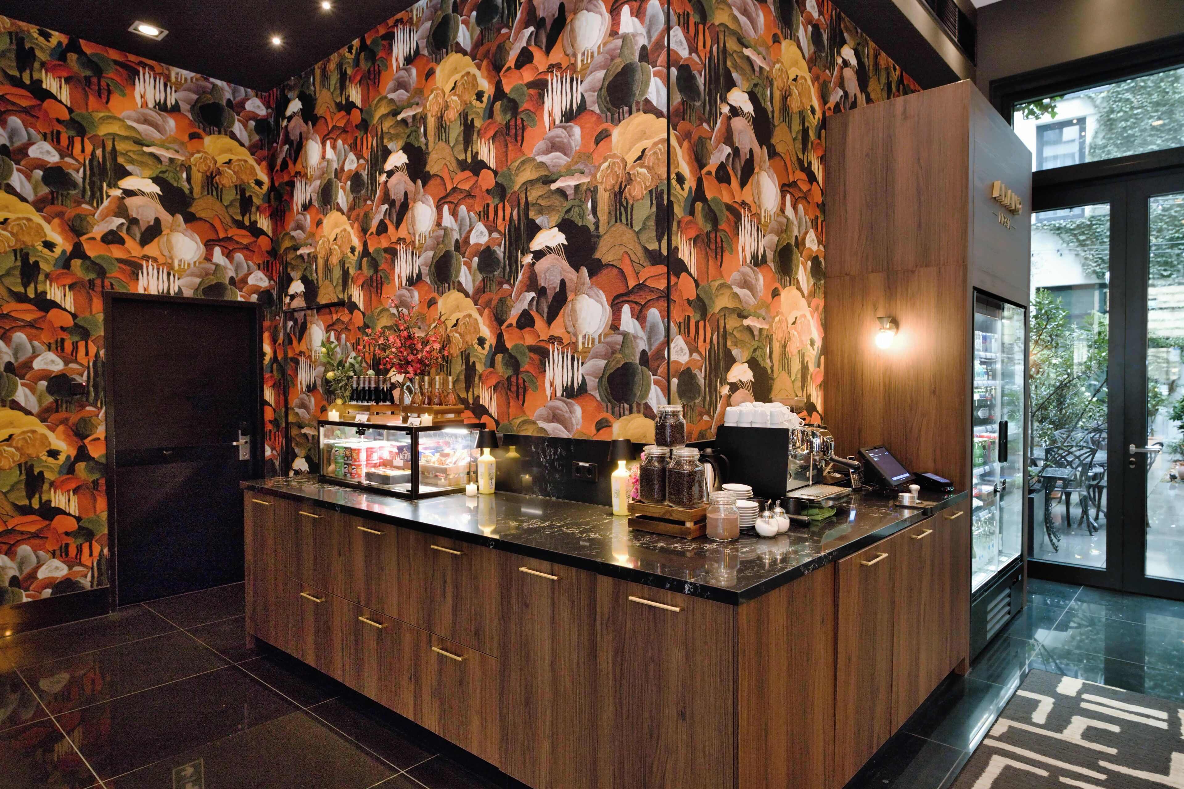 A modern kitchen with a wooden countertop, a coffee station, and a decorative wall mural.