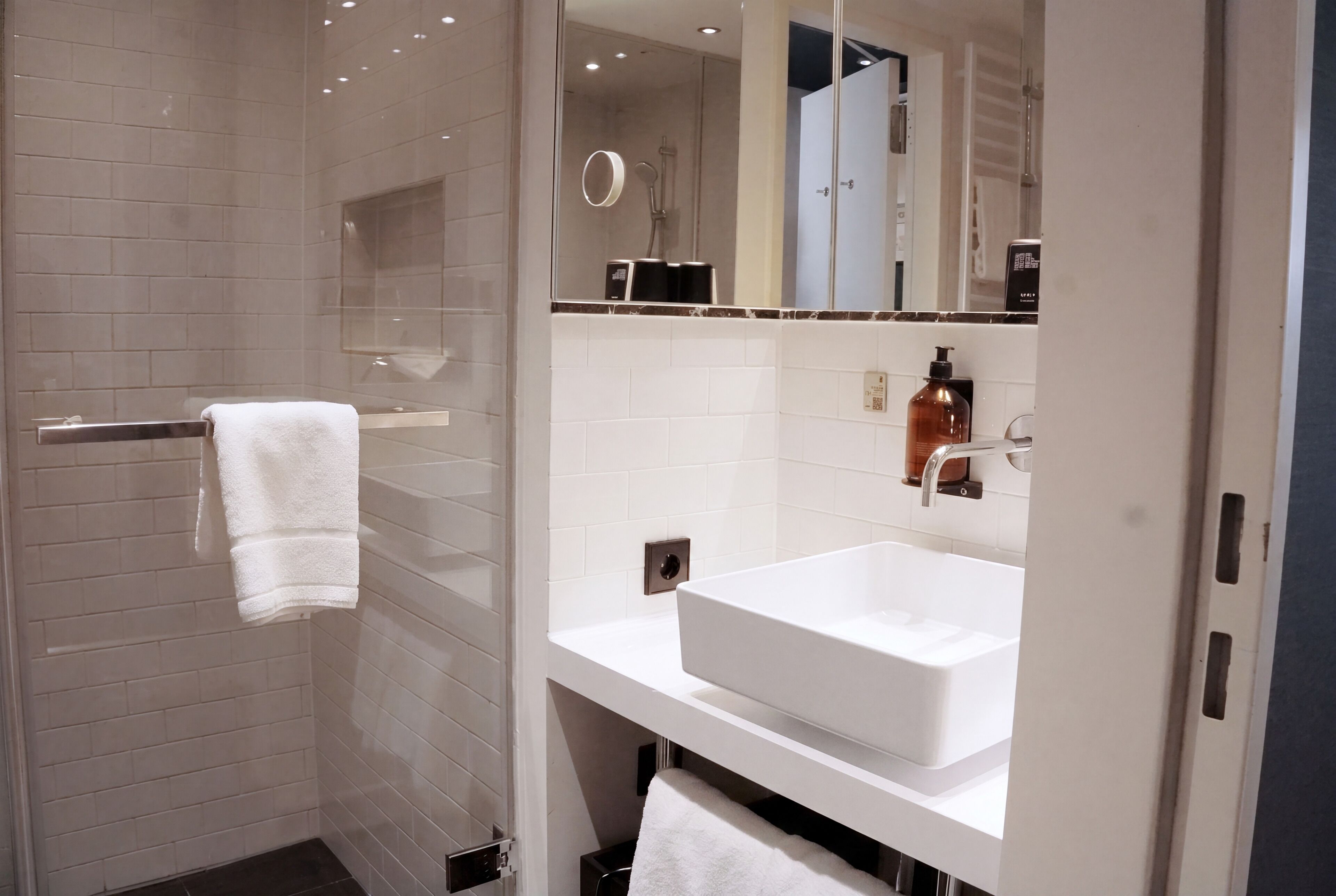 A modern bathroom with a walk-in shower, a white sink, and a mirror above the sink.
