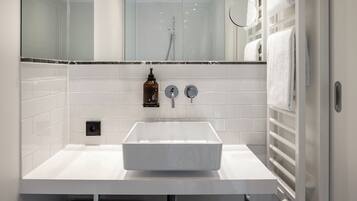 A modern bathroom with a white sink, a mirror, and a towel rack.