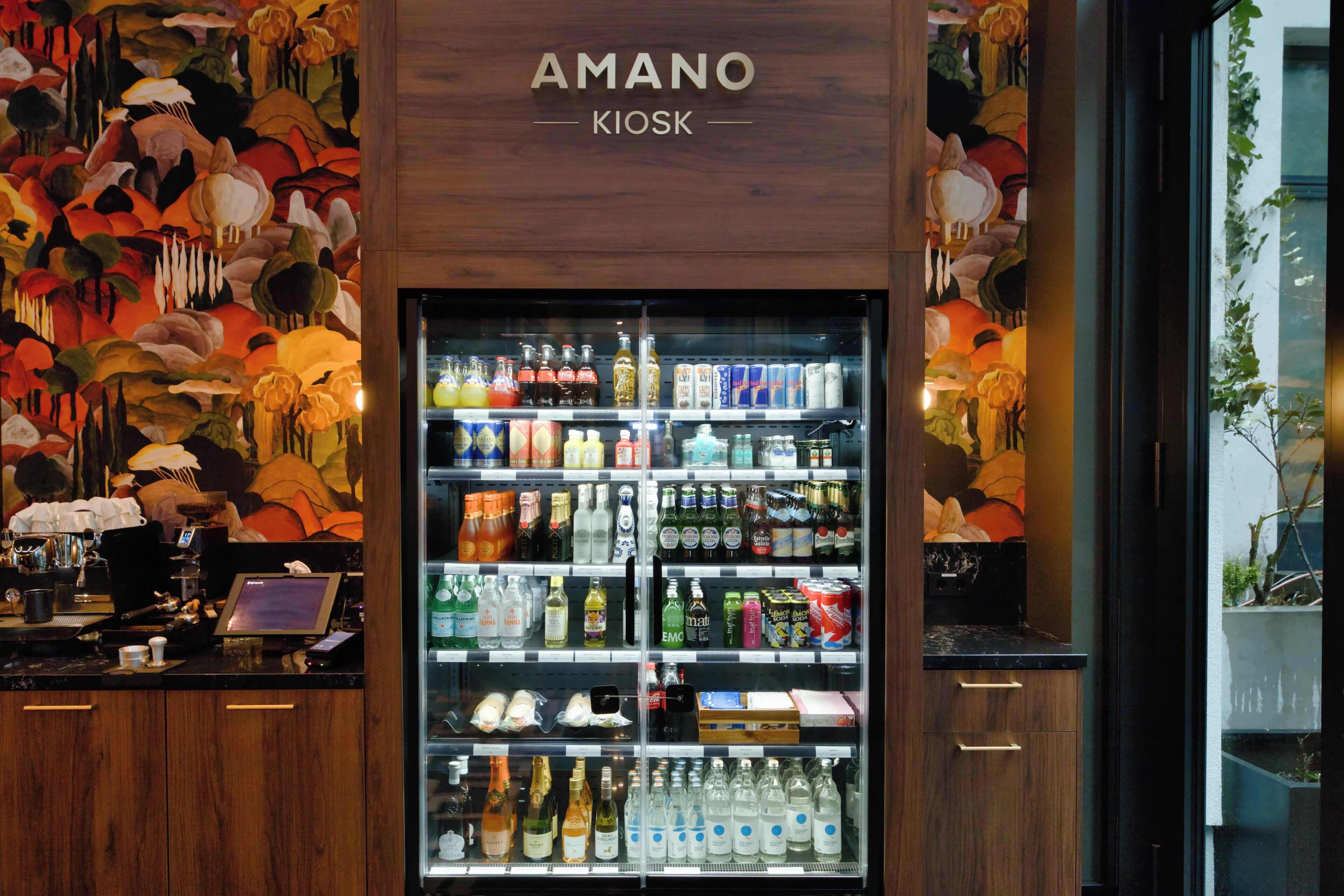 A minibar with a variety of beverages and snacks, a laptop, and a wooden counter.