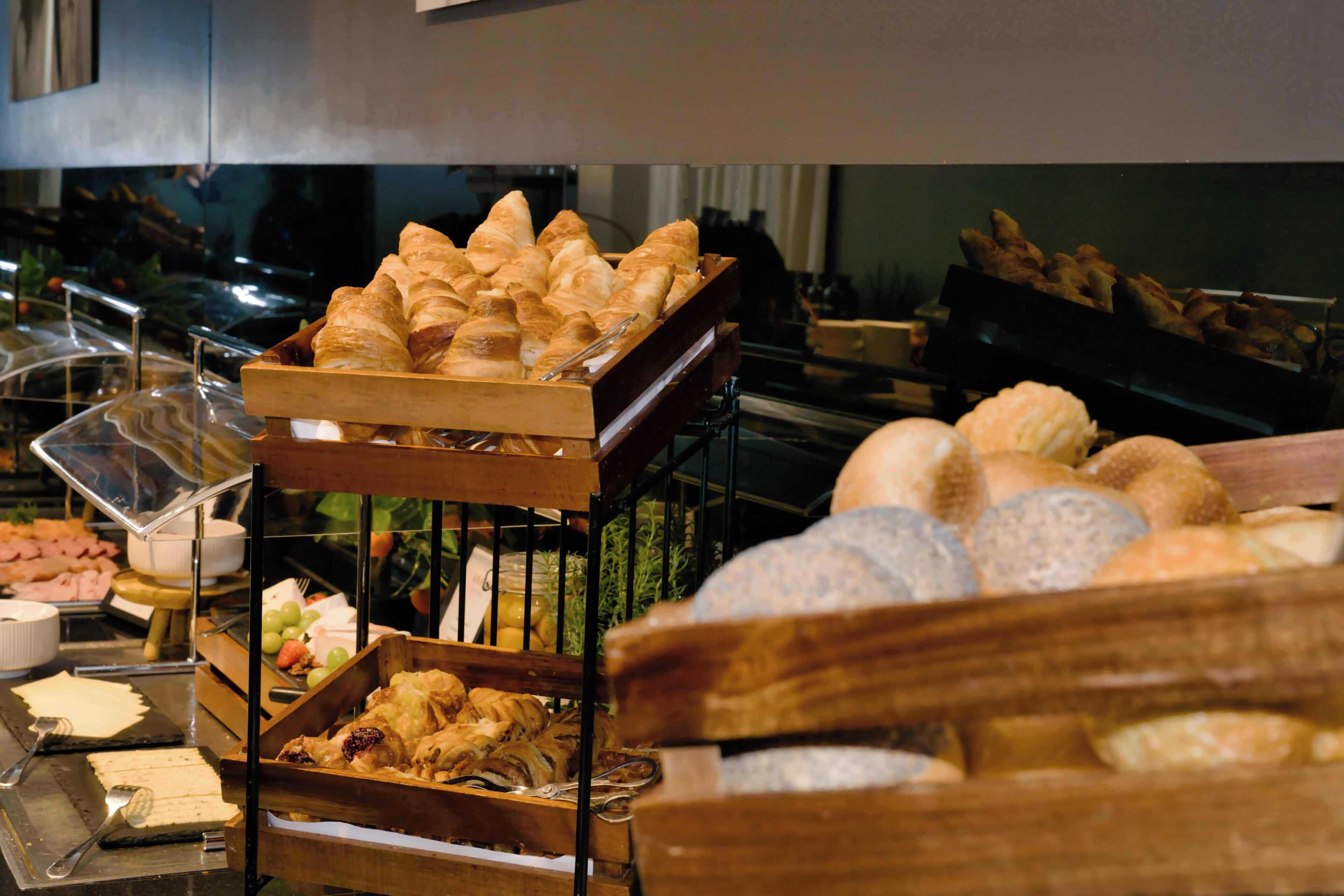 A buffet with various food items including pastries and bread.