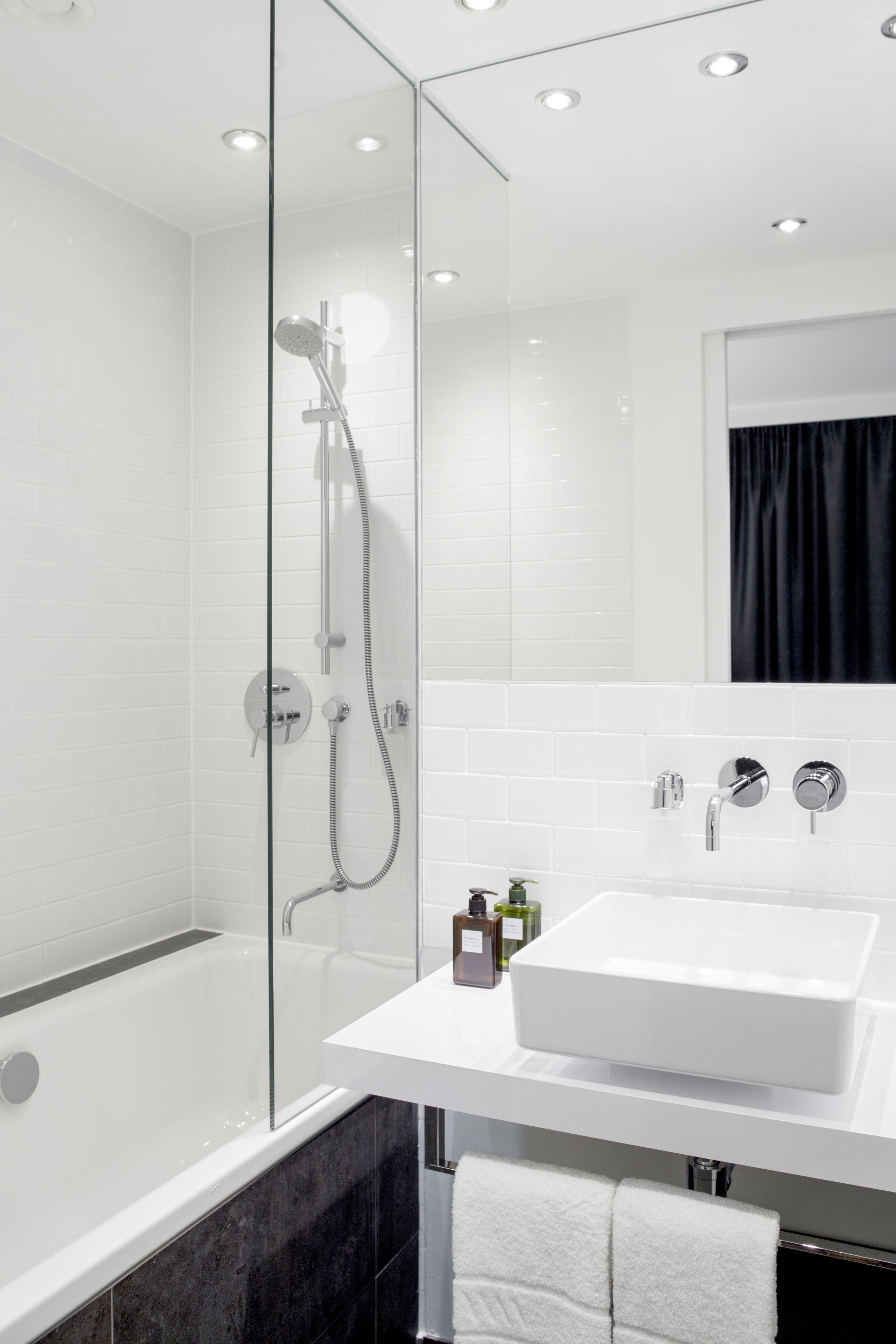 A modern bathroom with a glass-enclosed shower, a white sink, and a mirror above it.