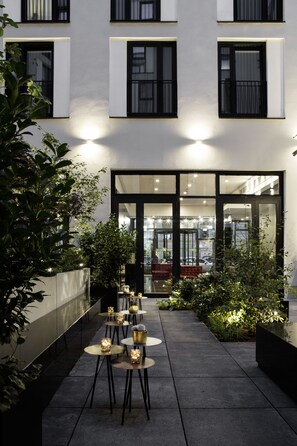 Un edificio moderno con un patio que tiene asientos al aire libre y plantas en macetas.