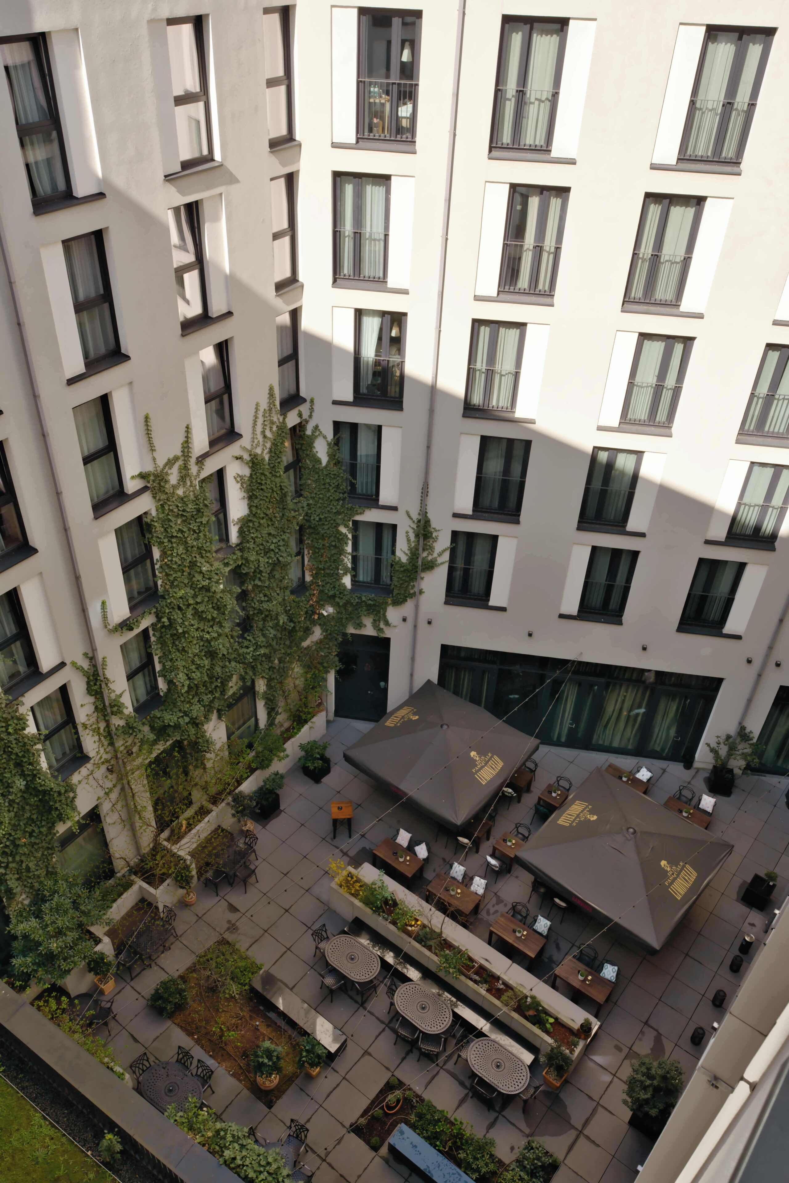 Un edificio de varios pisos con un patio que ofrece asientos al aire libre y áreas verdes.