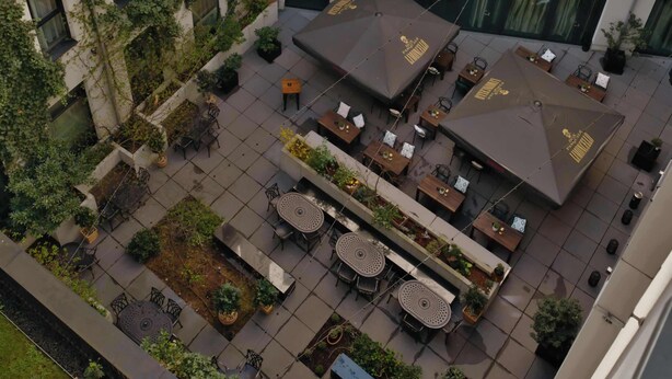 Un immeuble à plusieurs étages doté d’une cour intérieure aménagée avec des espaces de détente en plein air et de la verdure.