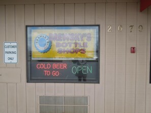 Une enseigne pour les magasins Brewsky's Bottle Shops, avec des néons indiquant « BIÈRE FRAÎCHE À EMPORTER » et « OUVERT ».
