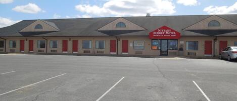 A motel with a large parking lot and a sign for Nittany Budget Motel and Brewsky's Bottle Shop.