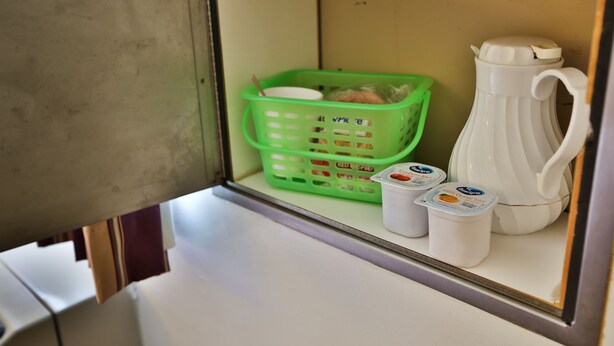 A small kitchenette with a green basket, a white pitcher, and two containers of yogurt. - Nittany Budget Motel (State College)