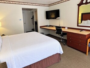 Een hotelkamer met een bed, een bureau, een stoel, een televisie en een spiegel.