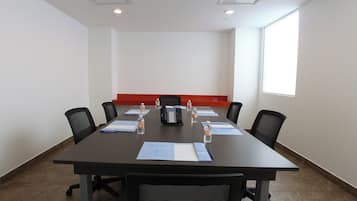A conference room with a long table, chairs, a telephone, and documents.