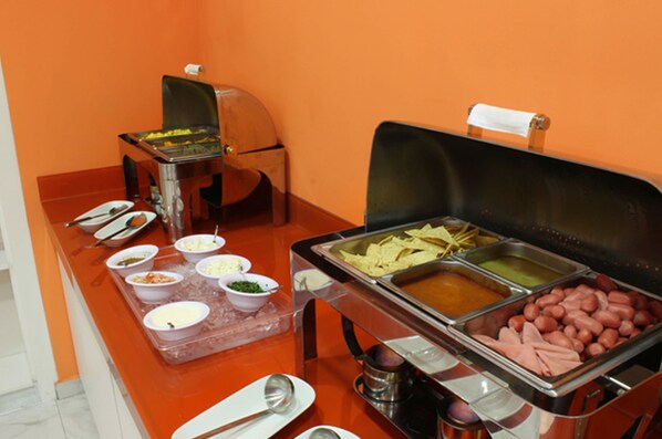 A buffet with various food items including hot dogs, nachos, and different dips.