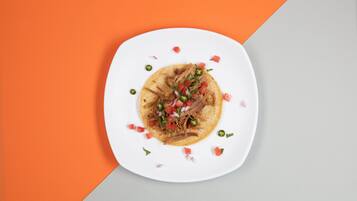 Un plato con un taco sobre una base blanca, rodeado de un fondo geométrico.