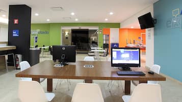 A modern office space with two Dell computers on a wooden table, surrounded by white chairs.