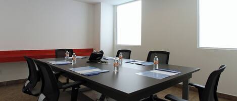 A conference room with a long table, four chairs, and a laptop.