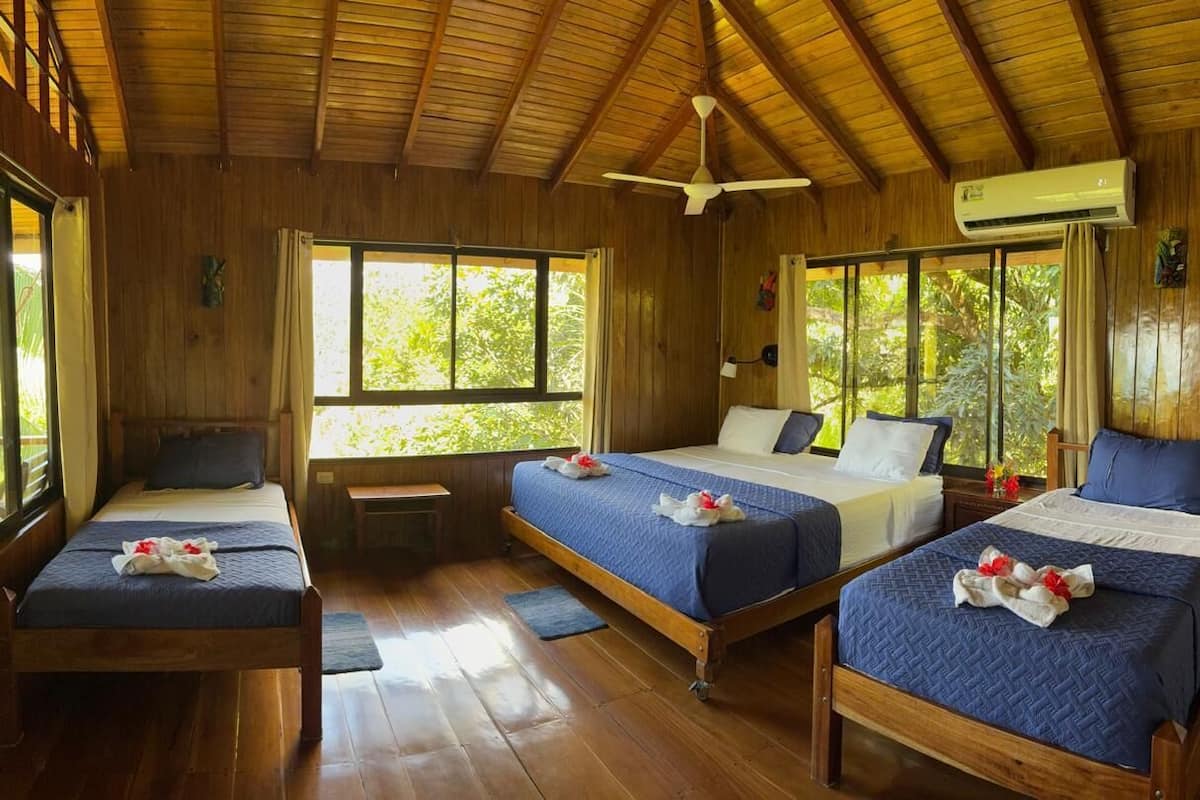 A wooden cabin with three bedrooms, each with a bed and a window.