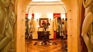 An interior with an arched doorway, a wooden floor, a table with a vase of flowers, and a framed picture on the wall. - San Juan Hotel (Cuenca)
