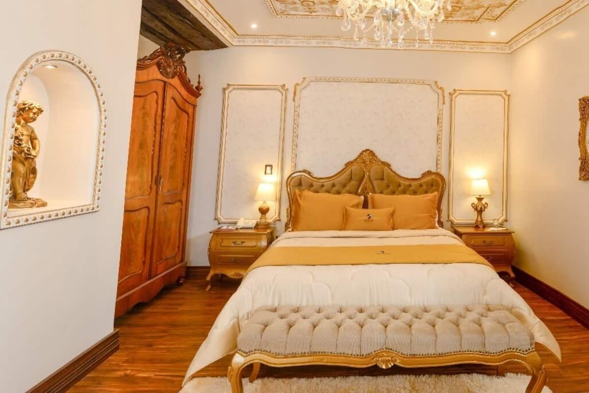 A luxurious bedroom with a large bed, ornate wooden wardrobe, and elegant decor.