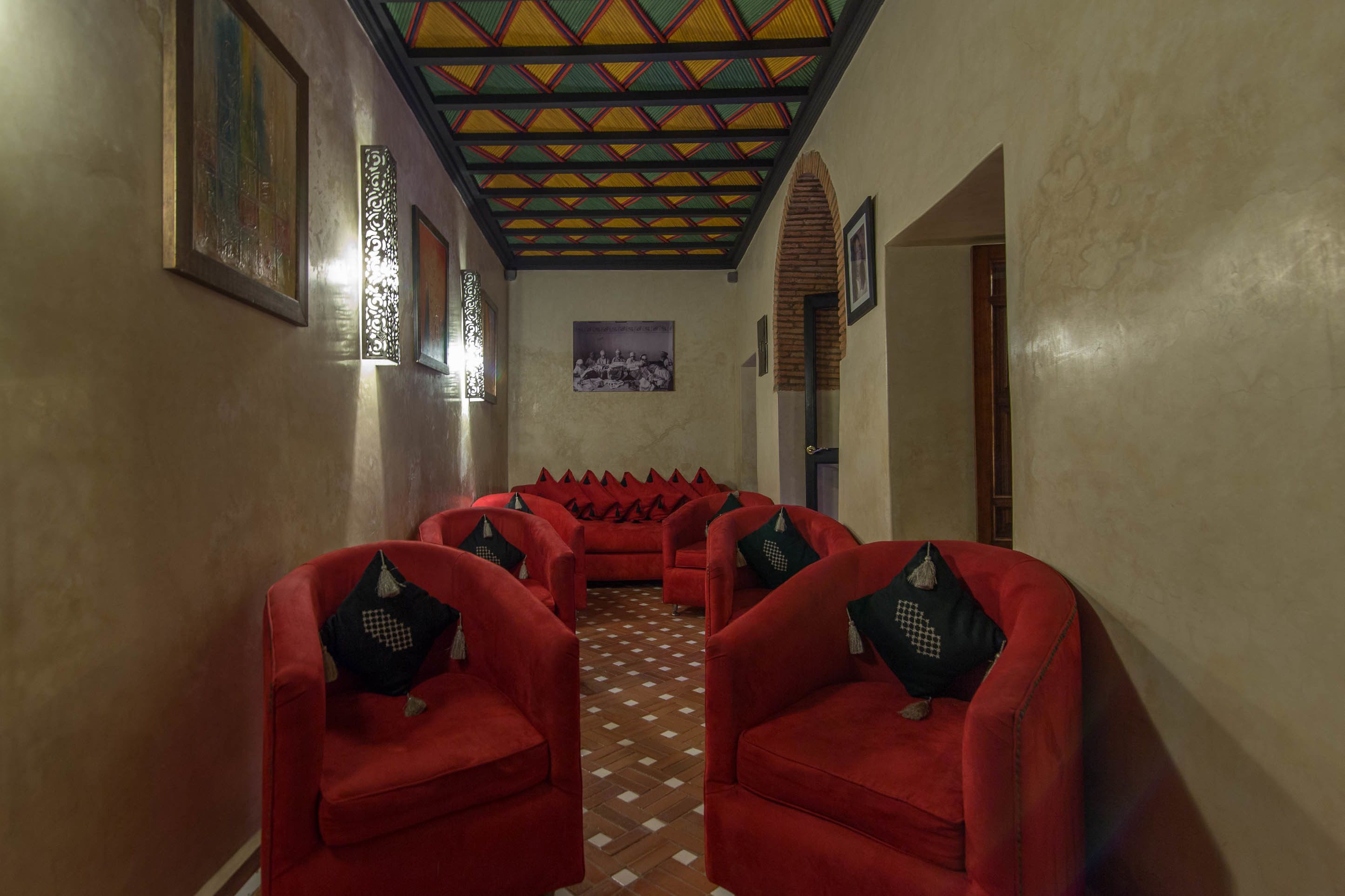 Un couloir avec des chaises rouges et un plafond à motifs.