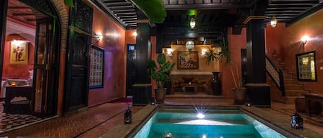 A pool area with a tiled floor, surrounded by walls with decorative elements and a staircase.