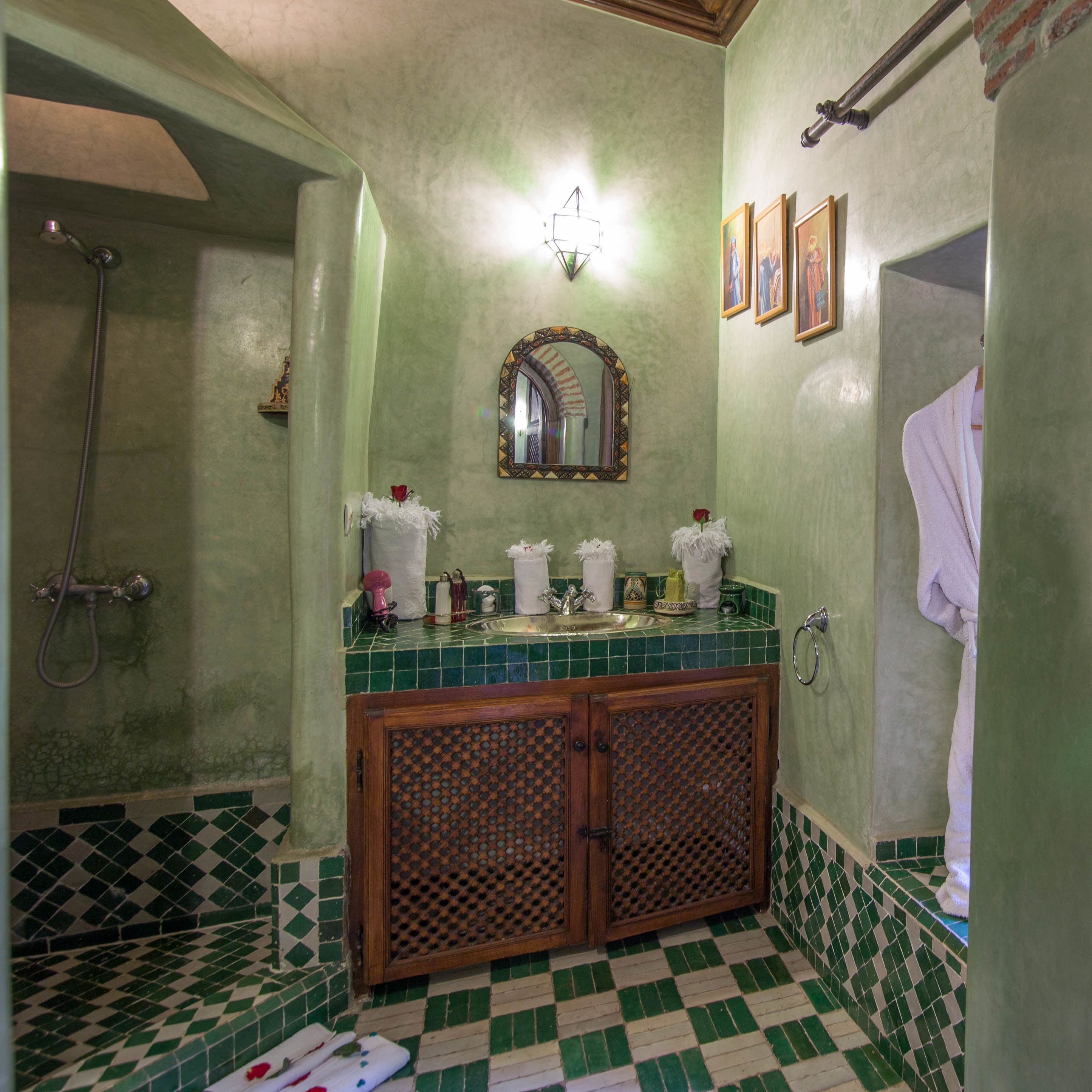 A bathroom with a green and white checkered floor, a wooden cabinet with a lattice design, a sink with a mirror above it, and a shower area.