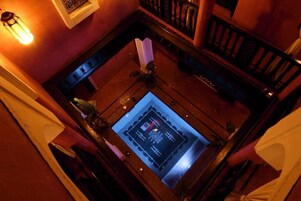 Una stanza con un grande schermo digitale sul pavimento, arredamento in legno e una lampada a sospensione.