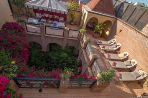 Una terraza en la azotea con sillones de descanso, un pequeño café y plantas en macetas.